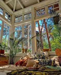 a bedroom with large windows and lots of plants