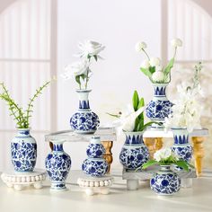 several blue and white vases with flowers in them sitting on a table next to each other