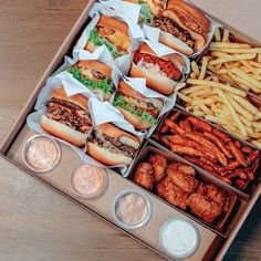 an open box filled with lots of different types of food next to some fries and condiments