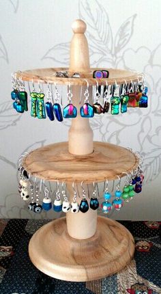 a three tiered wooden jewelry stand with many different colored beads hanging from it's sides