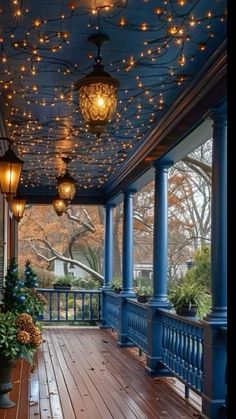 the porch is decorated with lights and potted plants on the wooden floor, along with hanging lanterns