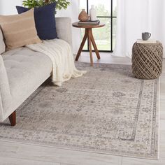 a living room area with a couch, rug and coffee table in front of a window