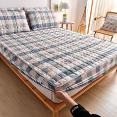 a person is holding up a mattress on a bed frame in a room with wooden floors