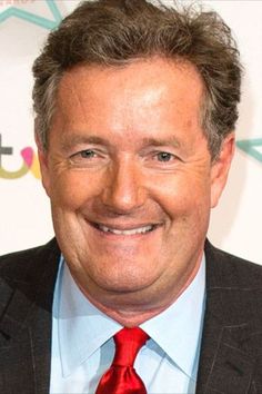 a man in a suit and red tie smiling at the camera with his hand on his hip