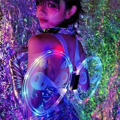 a woman wearing a futuristic outfit and holding a circular object in her hands with glowing lights around her