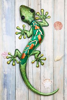 a green and orange lizard sitting on top of a wooden wall