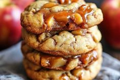 three cookies stacked on top of each other with caramel toppings and apples in the background