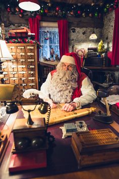 a man dressed as santa claus sitting at a desk in an old - fashioned office