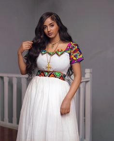 This stunning Habesha Kemis is a true work of art, with its luxurious Menen fabric, intricate Shimena dress, and colorful Tilf design. The Menen fabric, a type of Ethiopian silk, is known for its softness and lustrous sheen, and drapes beautifully over the body. The Shimena dress, a traditional Ethiopian embroidery style, adds an extra layer of elegance and texture to the dress. The colorful Tilf design, featuring bold geometric shapes and vibrant hues, is a true feast for the eyes and adds a pl Ethiopian Embroidery, Eritrean Dress, Ethiopian Dress, Habesha Kemis, African Fashion Traditional, Traditional Dresses, African Fashion, Custom Fit, Geometric Shapes