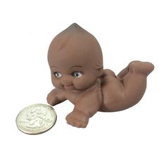 a little baby doll sitting next to a penny