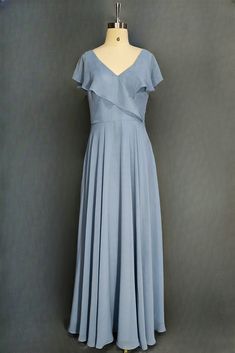 a blue dress on a mannequin stand in front of a gray wall and grey background