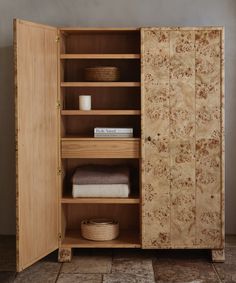 a wooden cabinet with two doors and shelves on the bottom, one door open to reveal towels