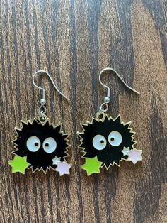 two black and green dangles with white stars on them, one has an evil face