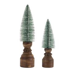 two small christmas trees sitting on top of wooden bases in front of a white background