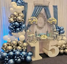 a table topped with balloons and cake next to a wall covered in blue and white decorations