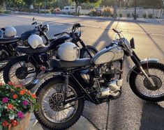 three motorcycles parked next to each other on the side of the road with flowers in front of them