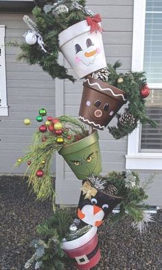 some christmas decorations are stacked on top of each other in front of a house with a snowman