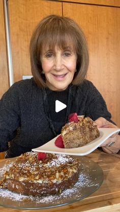 a woman sitting at a table with a plate of food in front of her and smiling