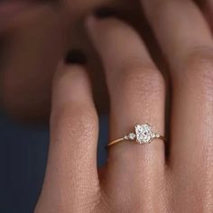 a woman's hand with an engagement ring on her finger and the other hand holding it