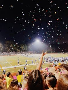 a group of people standing on top of a field under a sky filled with confetti