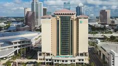 an aerial view of a large building in the middle of a city with tall buildings and palm trees