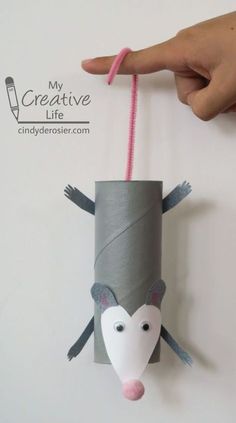 a hand holding a roll of paper with a mouse puppet on it's side