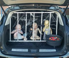 the back of a car with three baby dolls in it's caged area