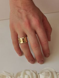 a person's hand with a gold ring on top of a white flower arrangement