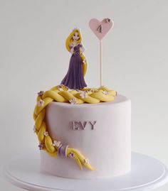 a birthday cake with a princess figurine on top and bananas around the base