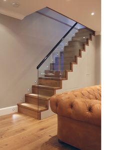 a brown couch sitting under a stair case