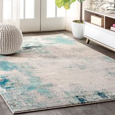 a living room area with a rug, chair and plant on the floor in front of it