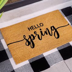 a welcome mat with the words hello spring on it in black and white checkers