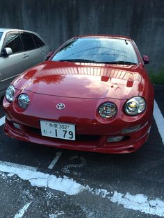 a red car parked in a parking lot next to another silver car on the street