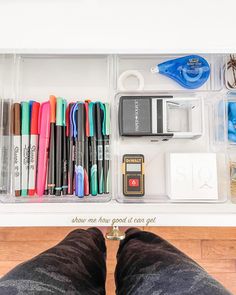 an organized drawer with pens, markers, and other office supplies on it's bottom shelf