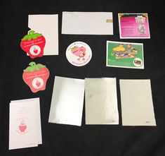 various papers and stickers are laid out on a black tablecloth, including an apple