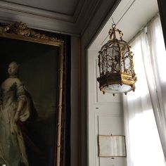 a birdcage hanging from the ceiling next to a painting