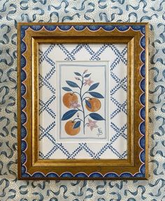 a painting hanging on the wall with blue and white designs in it's gold frame