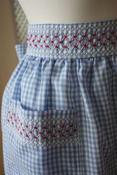 a close up of a dress on a mannequin's torso with red and white stitching