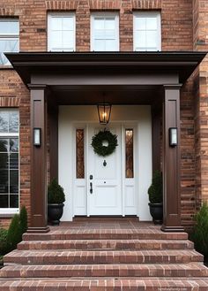 a white door with a wreath on it and steps leading up to the front door