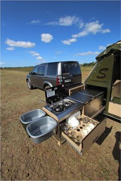 an suv is parked in the middle of a field with its hood open and it's cooking area opened