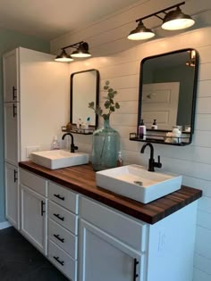 a bathroom with two sinks and mirrors on the wall, along with lights above them