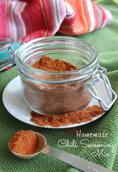 a jar filled with spices sitting on top of a white plate next to a spoon