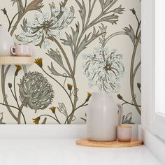 a white vase sitting on top of a counter next to a wallpaper covered in flowers