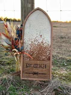 a wooden sign sitting on top of a grass covered field