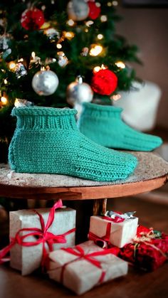 there is a christmas tree with presents under it and two pairs of socks on the table