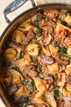 a pot filled with pasta and mushrooms on top of a wooden table