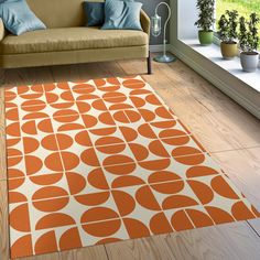 an orange and white rug with circles on it in a living room next to a couch