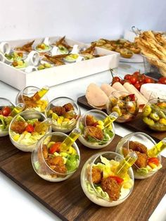 a wooden table topped with lots of bowls filled with different types of salads and appetizers