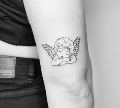 a small tattoo on the arm of a girl with an angel wings above her head