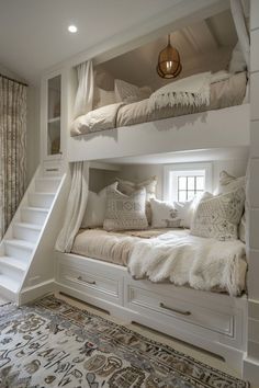 a white bunk bed sitting under a window next to a stair case with pillows on it